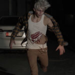 Model wearing large bloody claw marks silicone prosthetic attached to round neck mesh sleeveless shirt