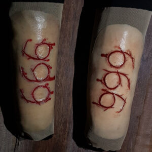 666 carved into flesh silicone prosthetic attached to pair of mesh gauntlets